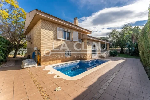 Vista frontal de un chalet de lujo en Vilafortuny con fachada de ladrillo visto y jardín exuberante